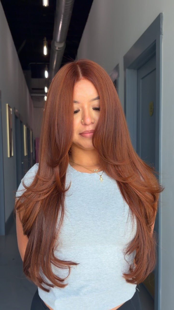 Woman showing long, center-parted honey brown hair with warm red tones