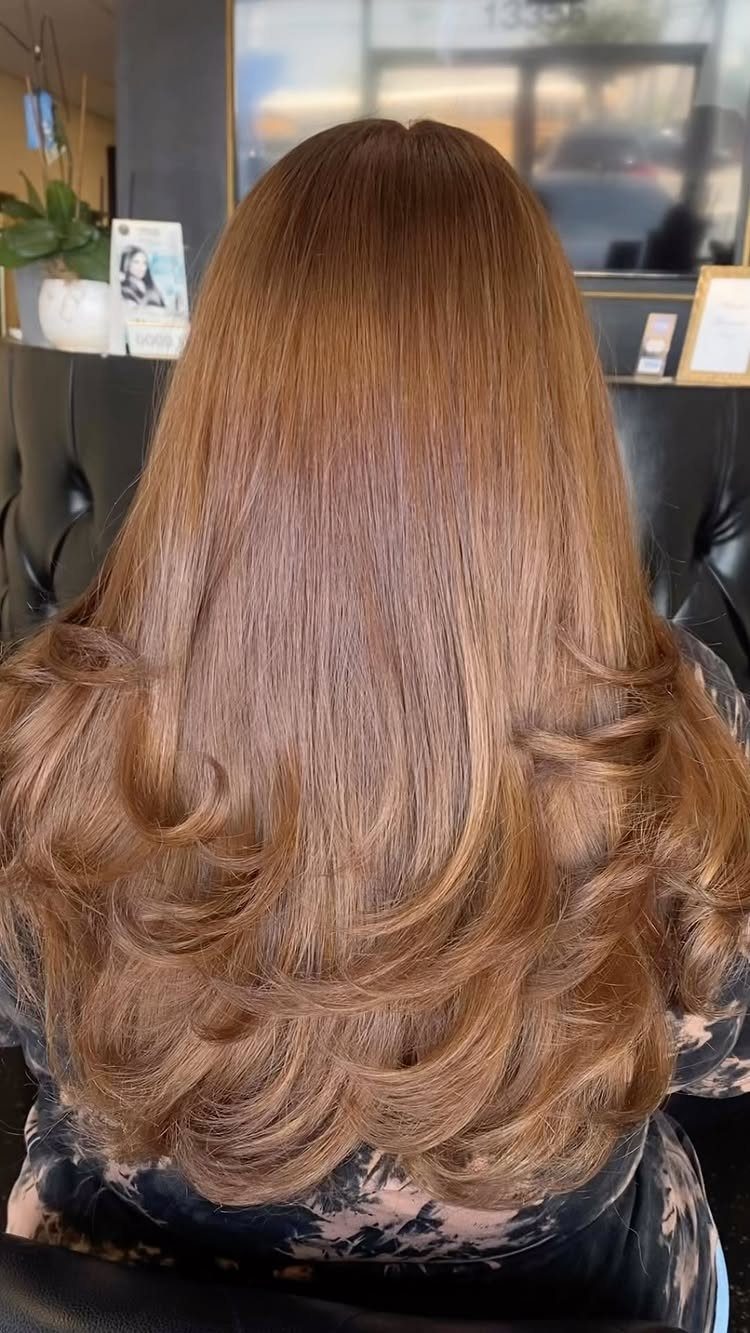 Long honey caramel brown hair with softly curled ends in a salon
