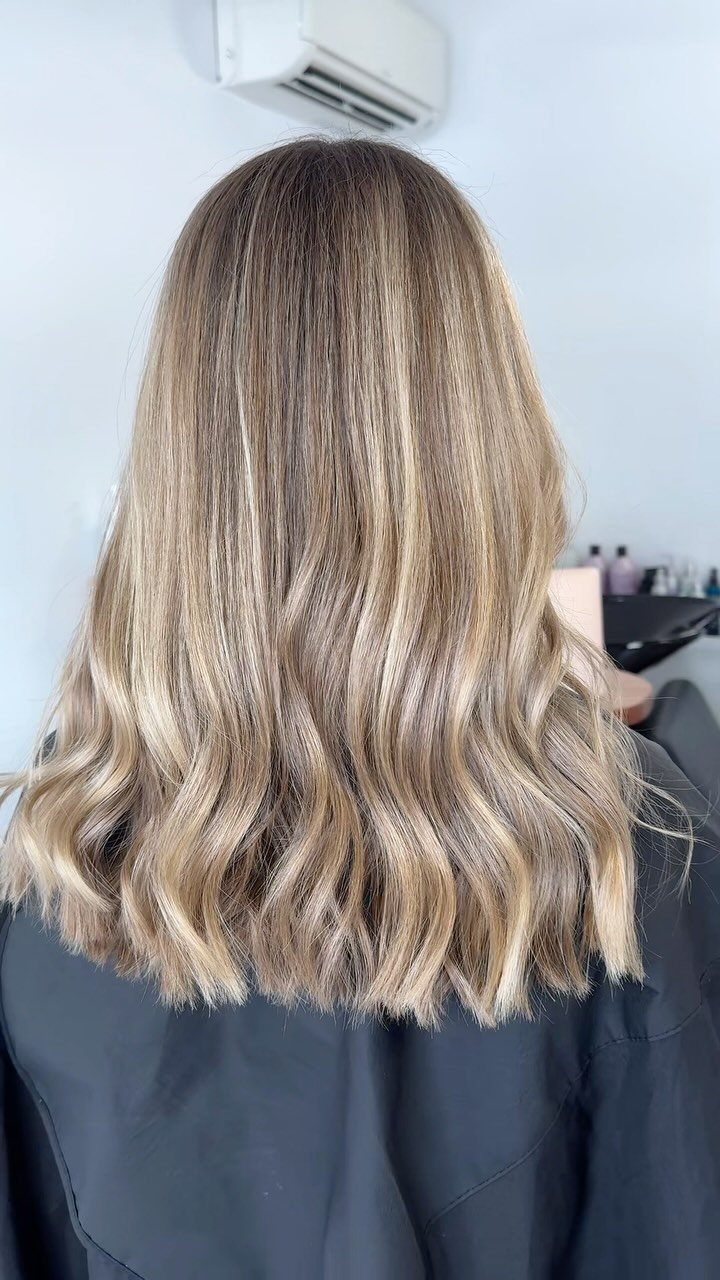 Long wavy light brown hair with golden caramel highlights in a salon