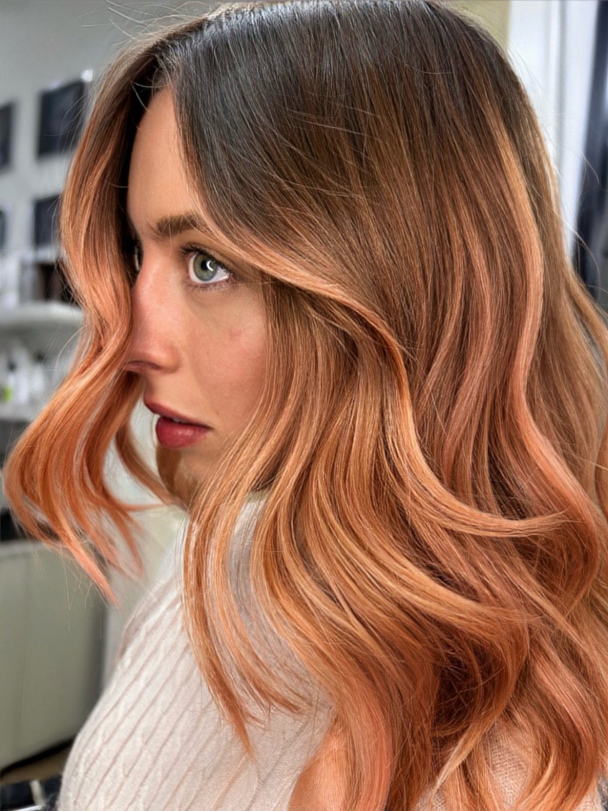 Woman showing long wavy peachy honey-blonde hair with darker roots