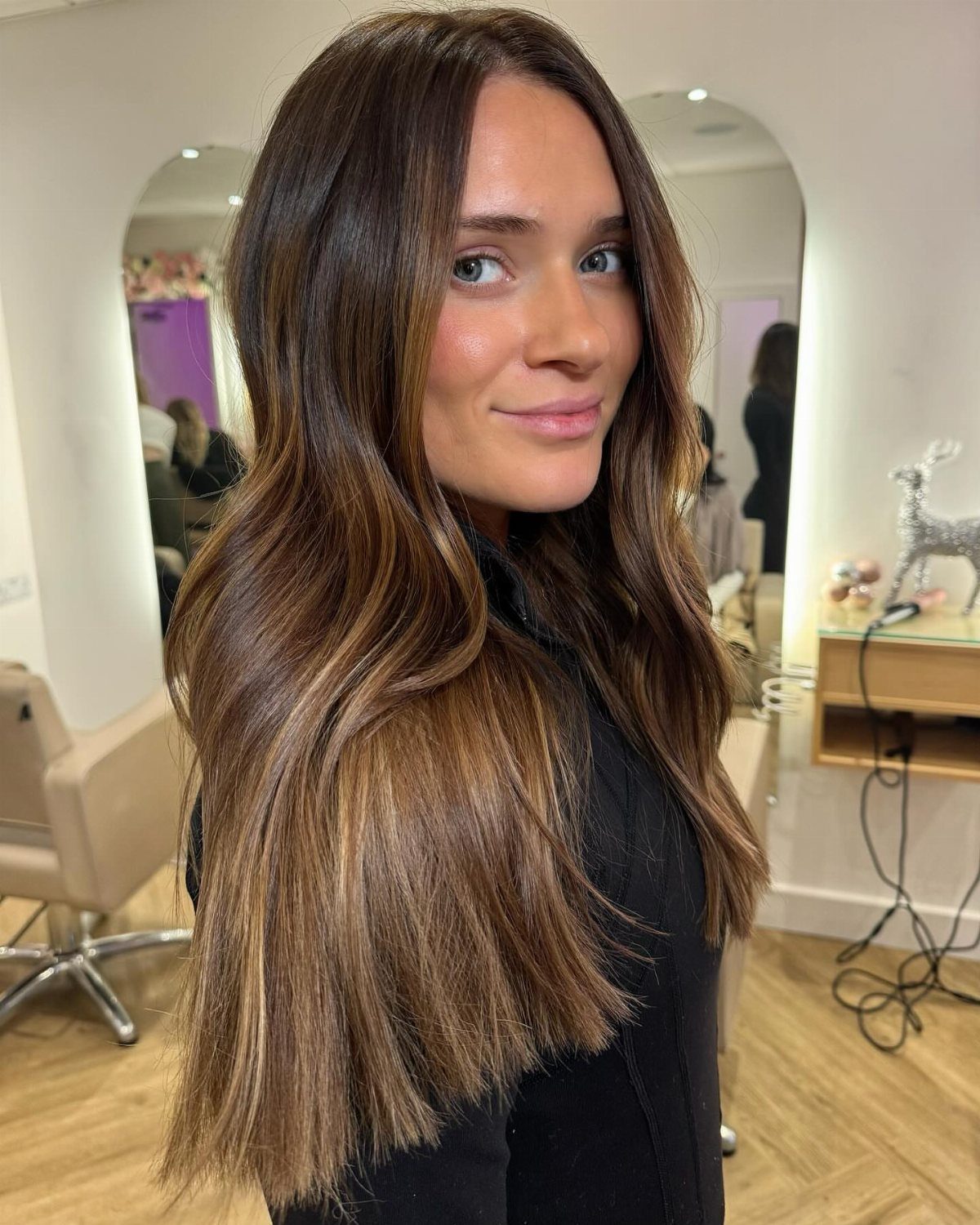 Woman with long brunette hair warmed by honey-brown highlights and darker roots