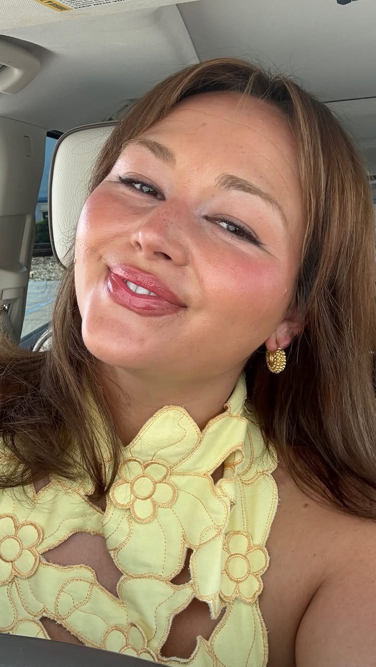 Woman with long golden brown hair posing in a car