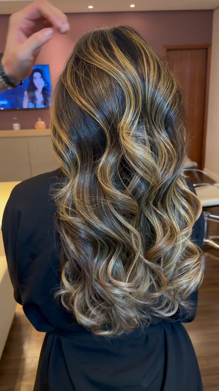 Long brunette curls with champagne balayage highlights in a salon