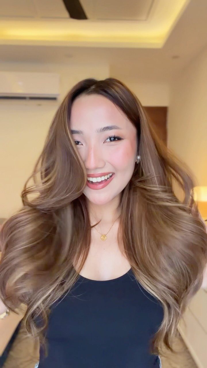 Woman with long wavy honey brown hair and lighter highlights