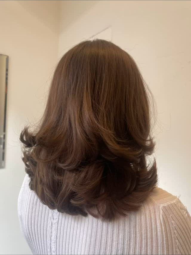 Shoulder-length honey brown hair with copper tones and curled layered ends