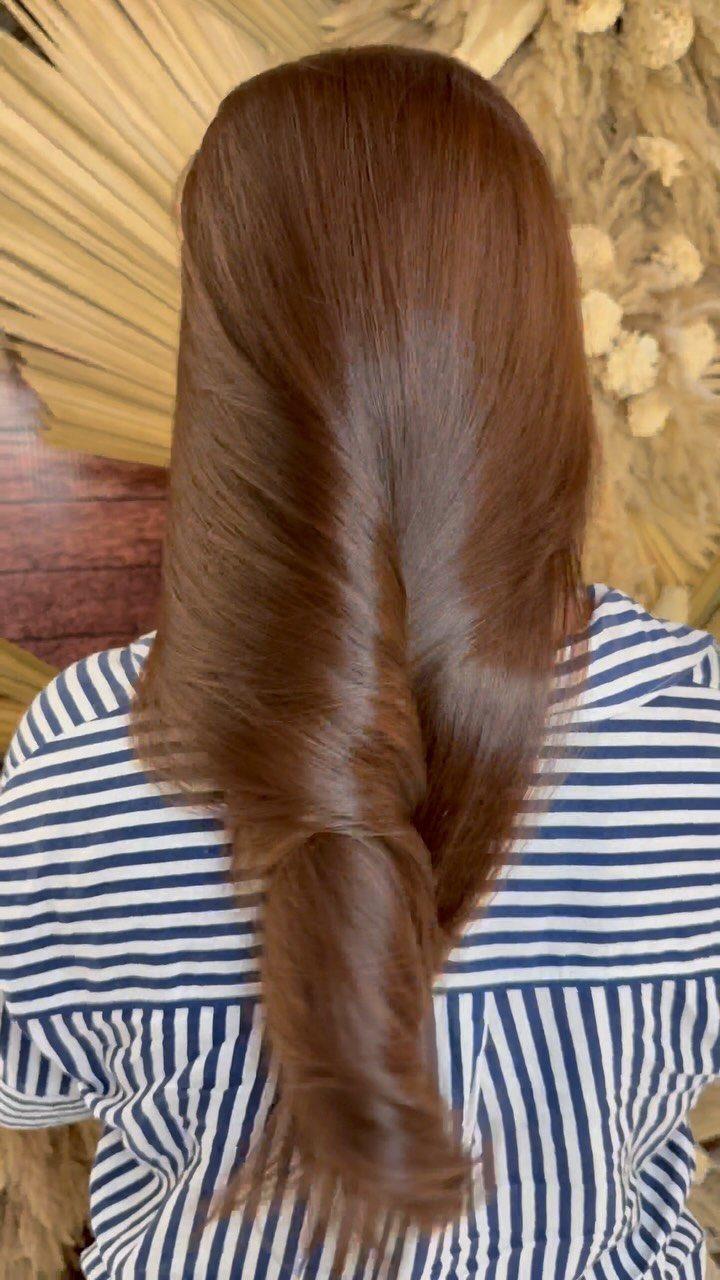 Glossy honey brunette hair gathered into a low twisted ponytail