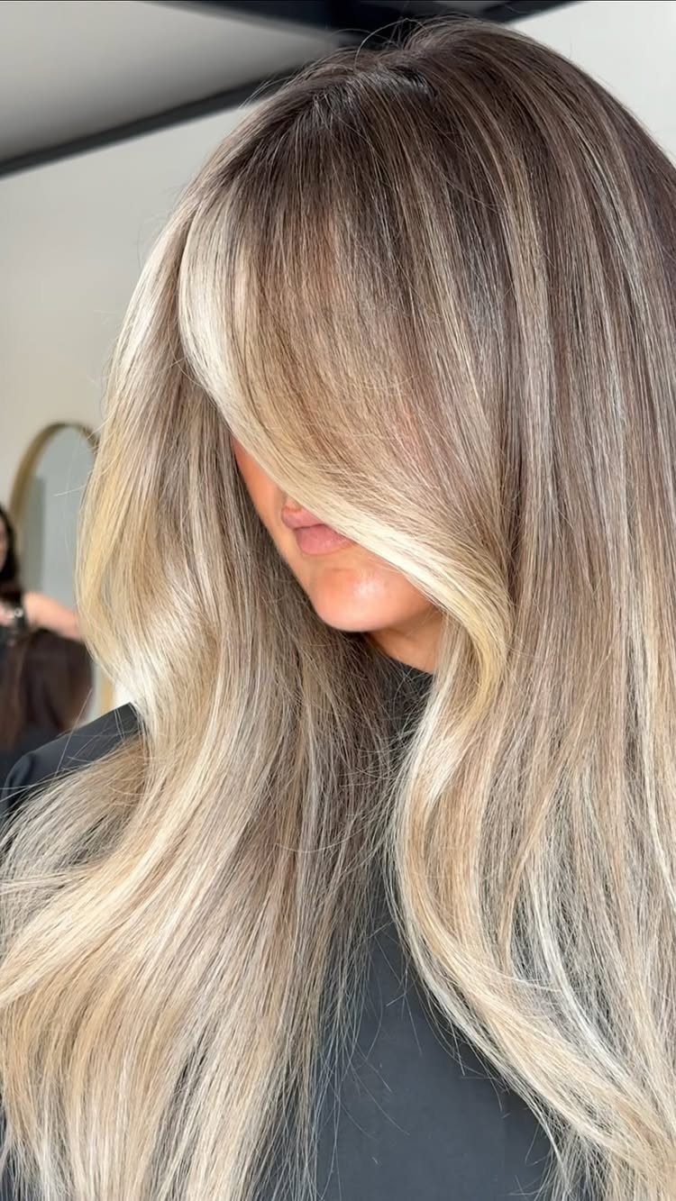 Long dark-rooted hair fading into icy blonde balayage lengths and ends