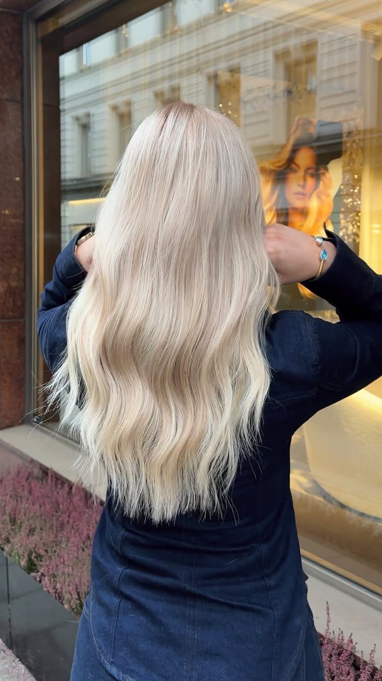 Long, wavy platinum blonde hair falls over a dark navy top