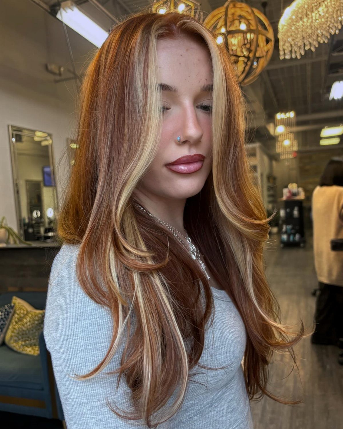 Woman with long copper hair and pale blonde highlights in a salon