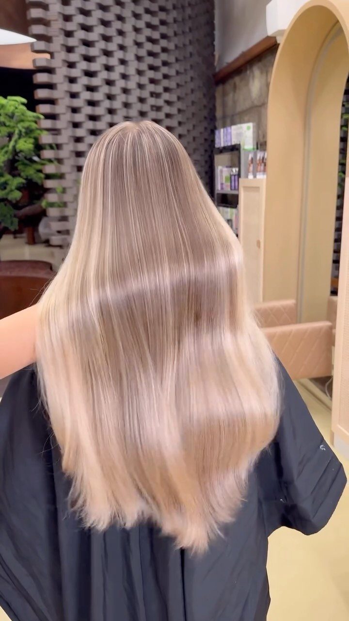Long icy blonde hair with fine highlights falls down a salon client’s back