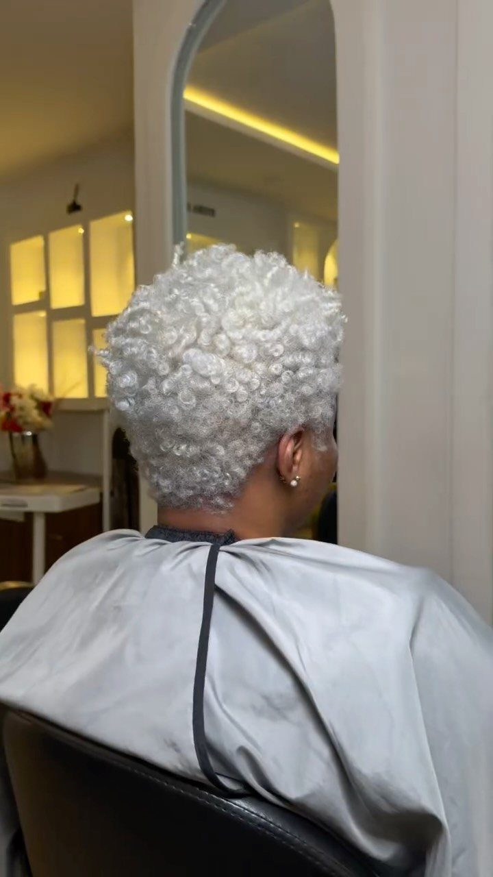 Short icy platinum curls shown from behind in a salon chair