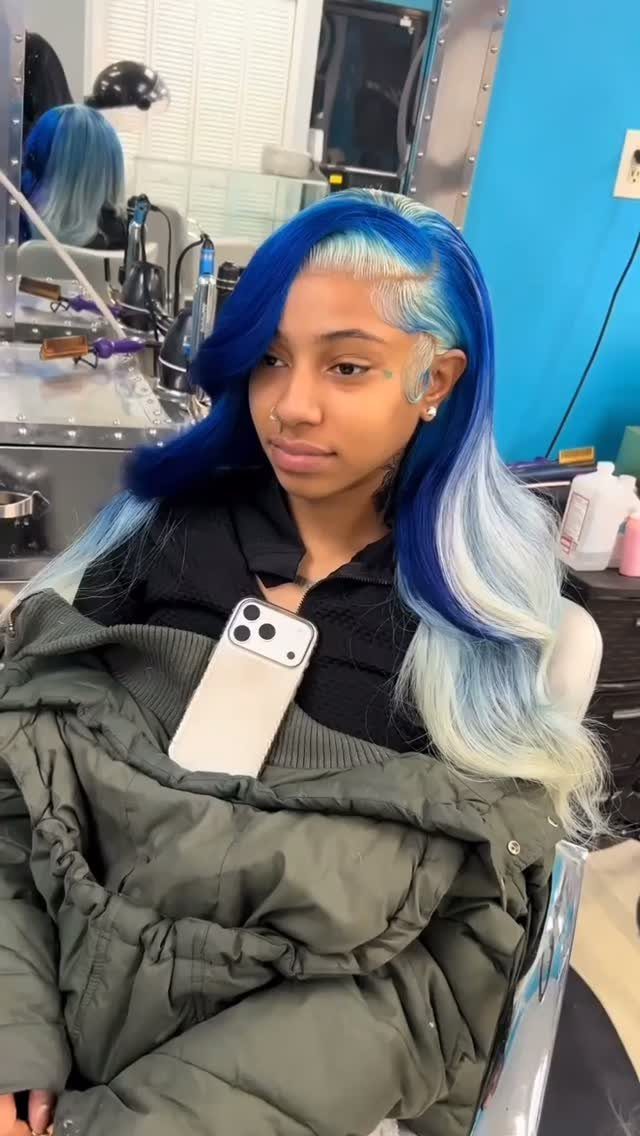 Person with long wavy vivid blue and icy blonde hair seated in a salon