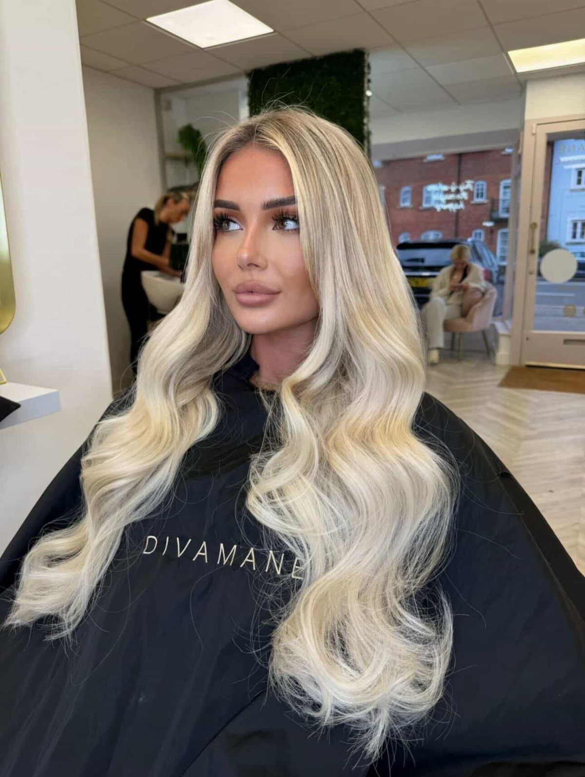 Woman with long platinum blonde hair blending into pale, softly waved ends