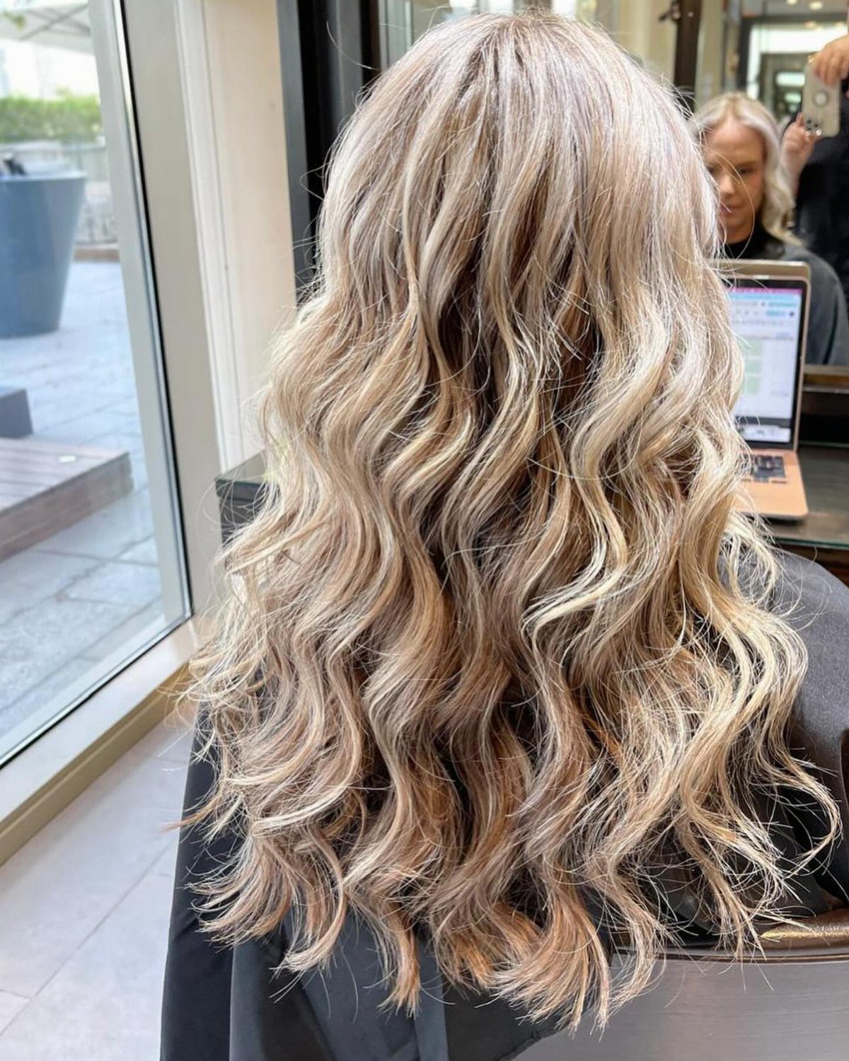 Long wavy sandy platinum blonde hair with pale highlights in a salon
