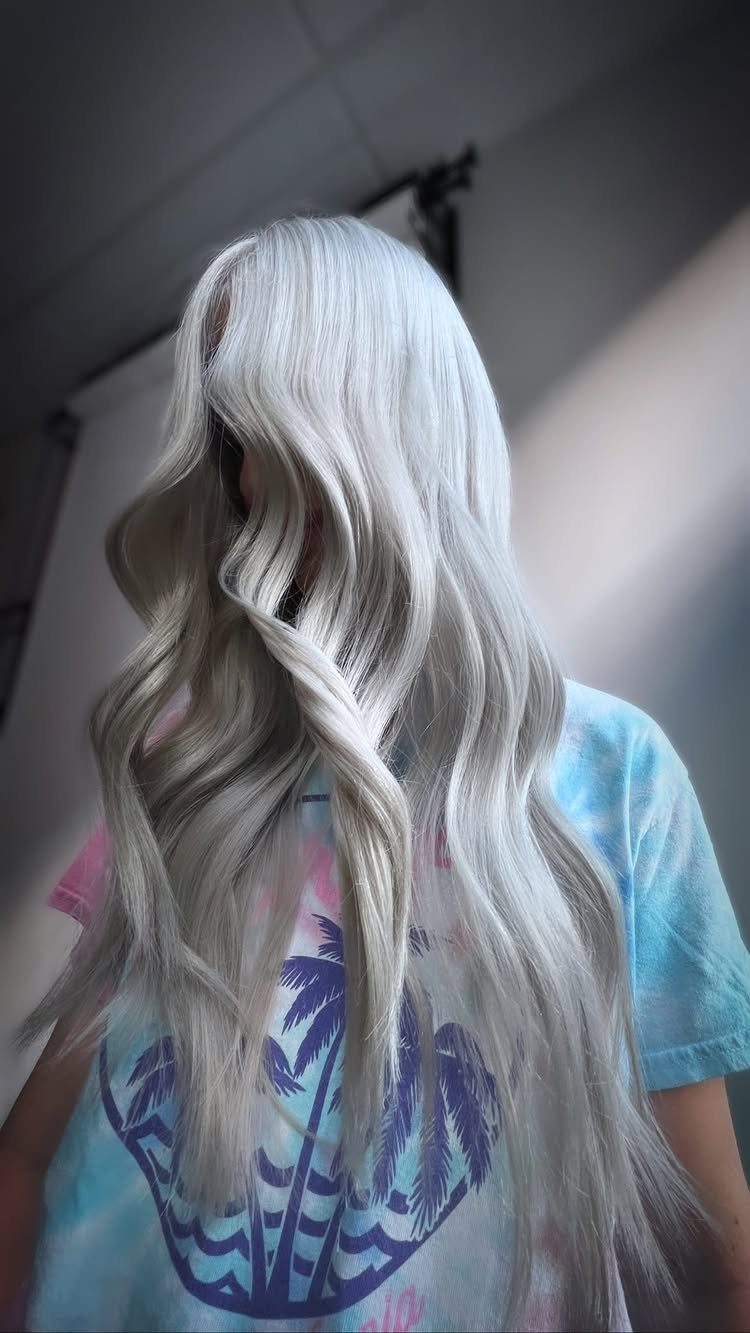 Long silver-platinum waves fall over a person’s tie-dye shirt