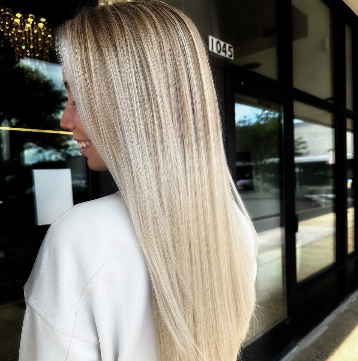 Long straight vanilla blonde hair with subtle highlights falls over a woman's white top.