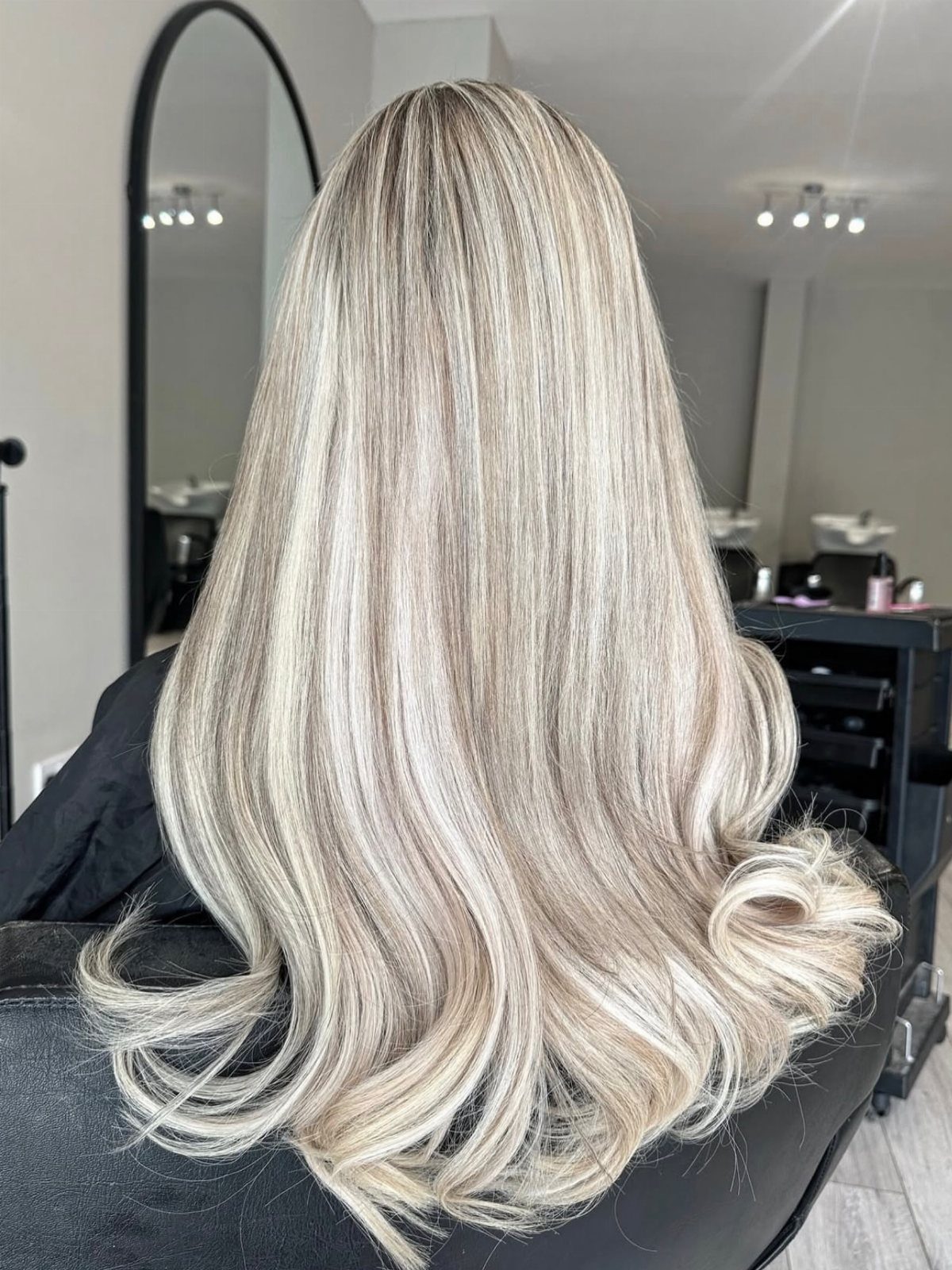 Long white-blonde hair with softly curled ends in a salon chair