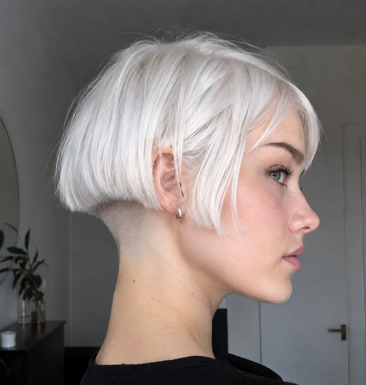 Woman showing a short icy white-blonde bob with a closely cropped nape