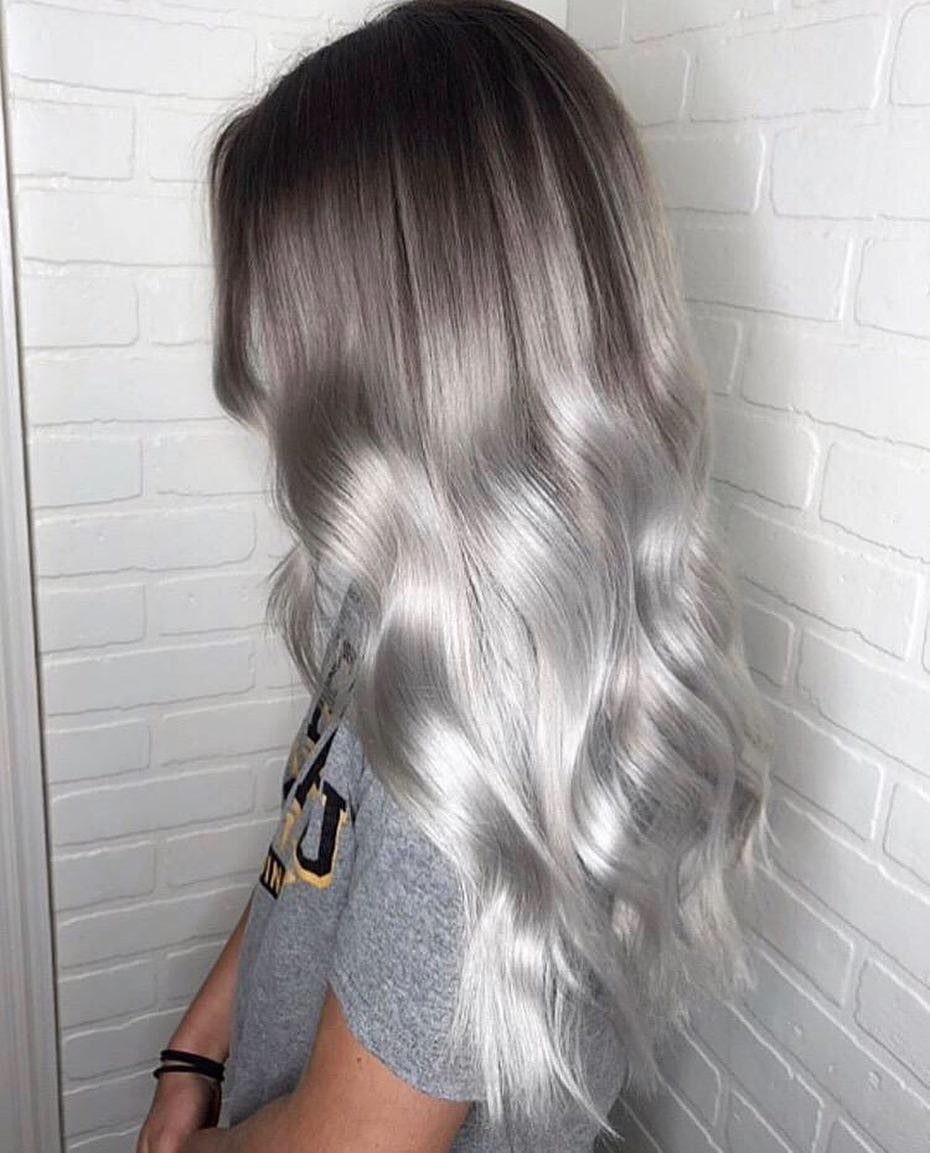 Long wavy hair fading from dark ashy roots to icy platinum ends