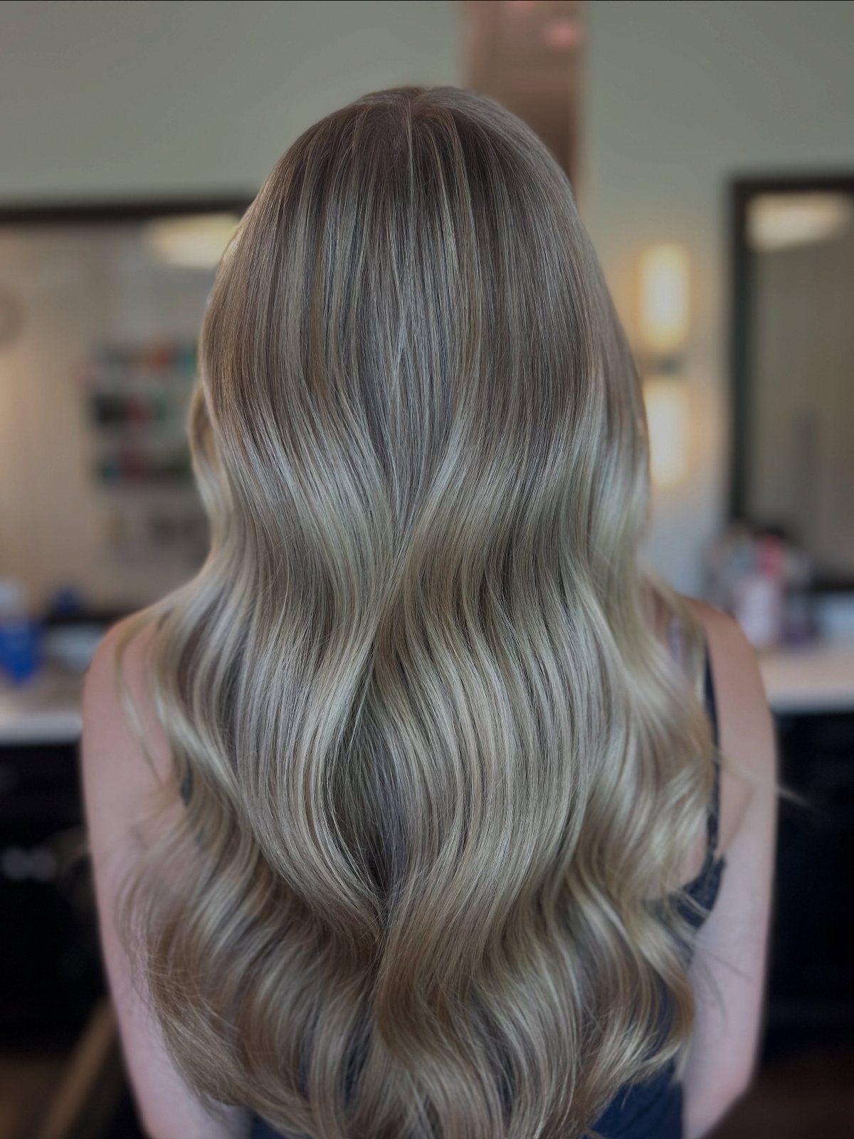 Long dark-rooted silver-blonde hair blends into loose waves