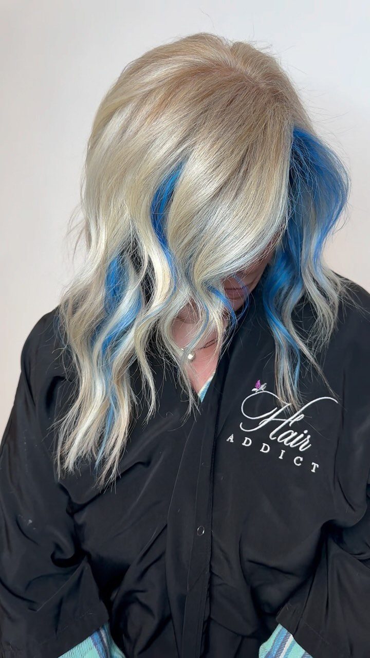Long wavy platinum blonde hair with vivid icy blue streaks framing the face