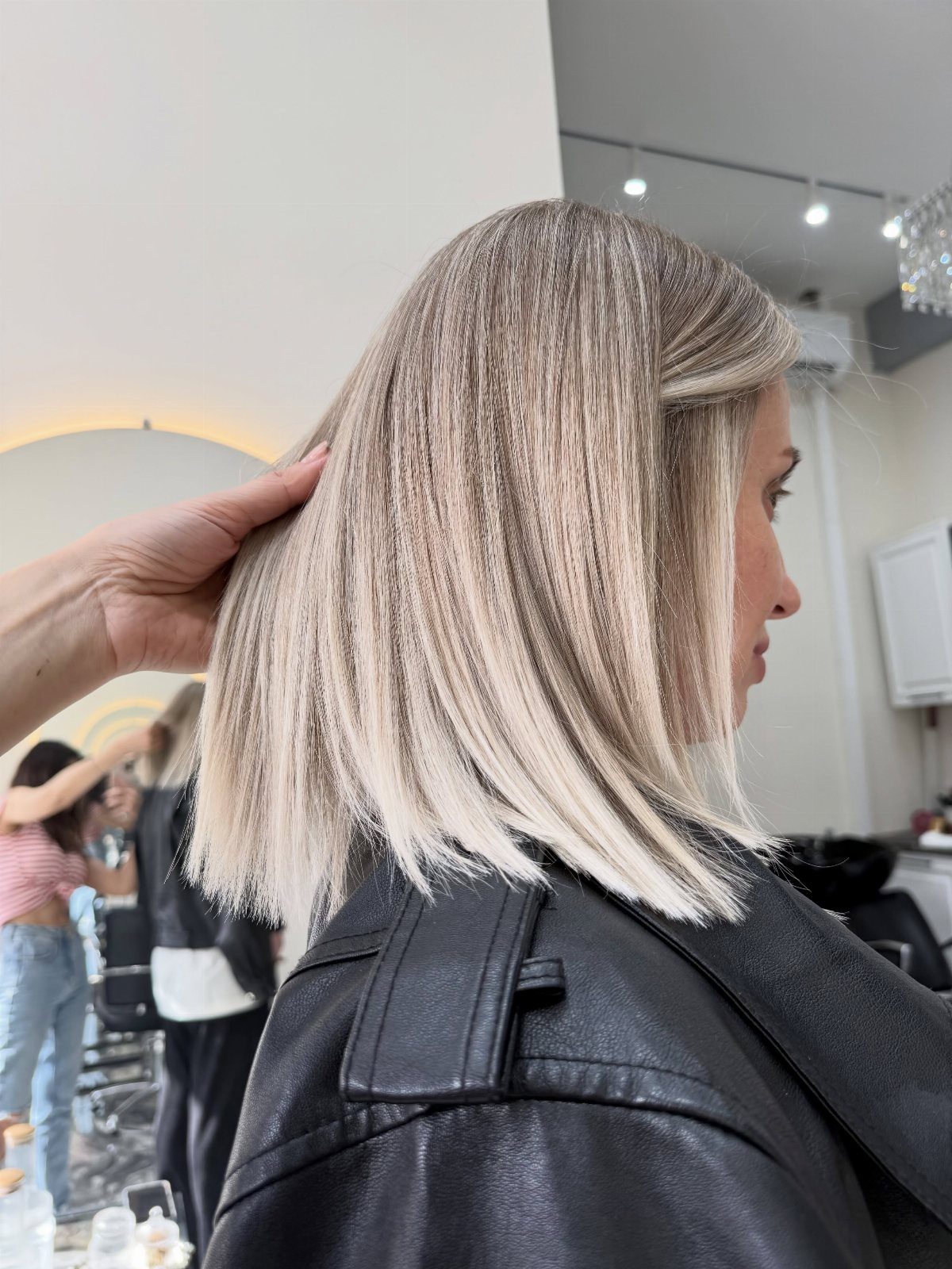 Shoulder-length icy blonde bob with darker roots in a salon