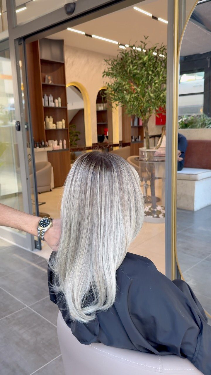 Long silver-white hair fades from ashy roots to platinum ends in a salon