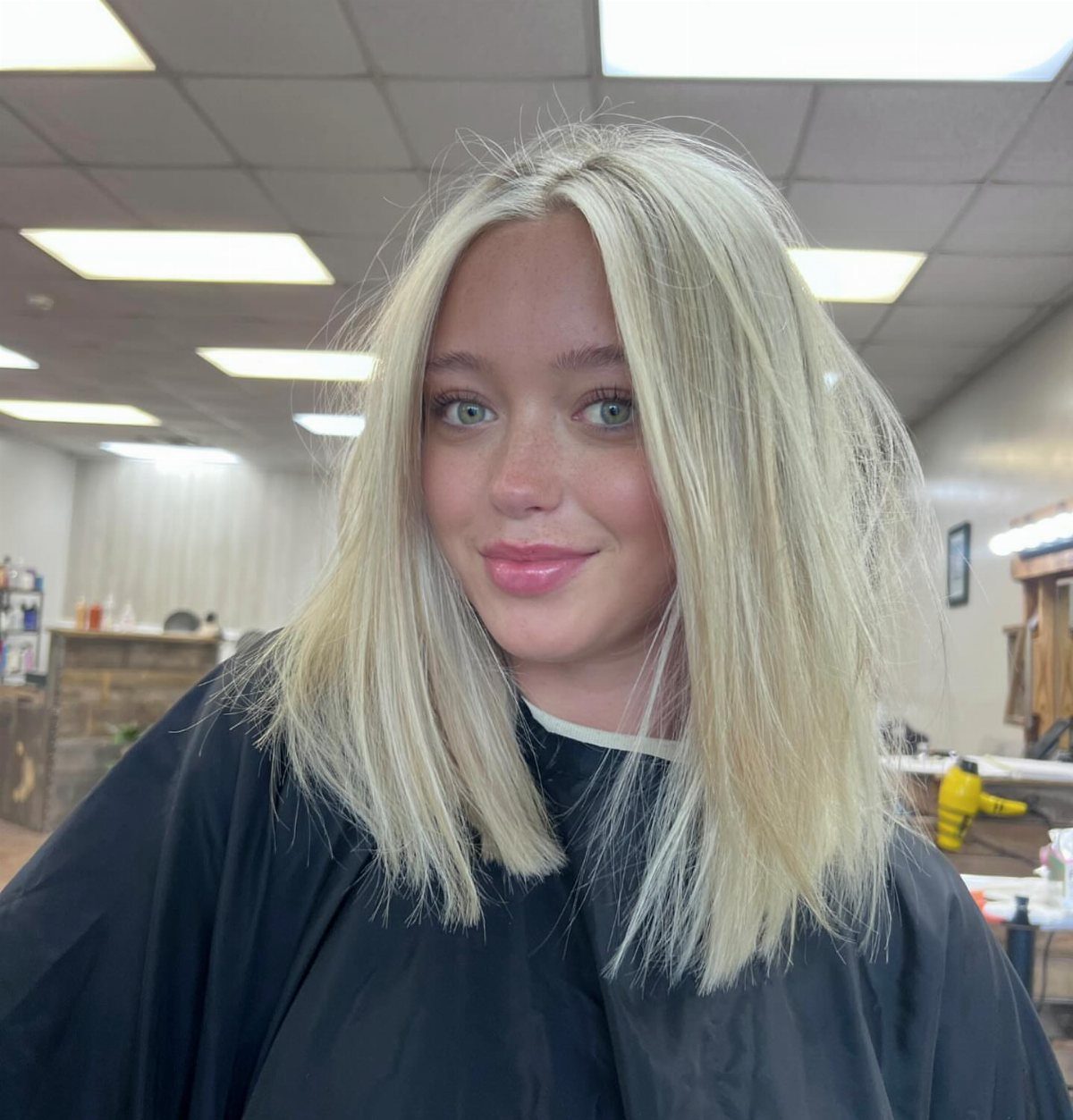 Woman with straight, center-parted icy white hair cut to shoulder length