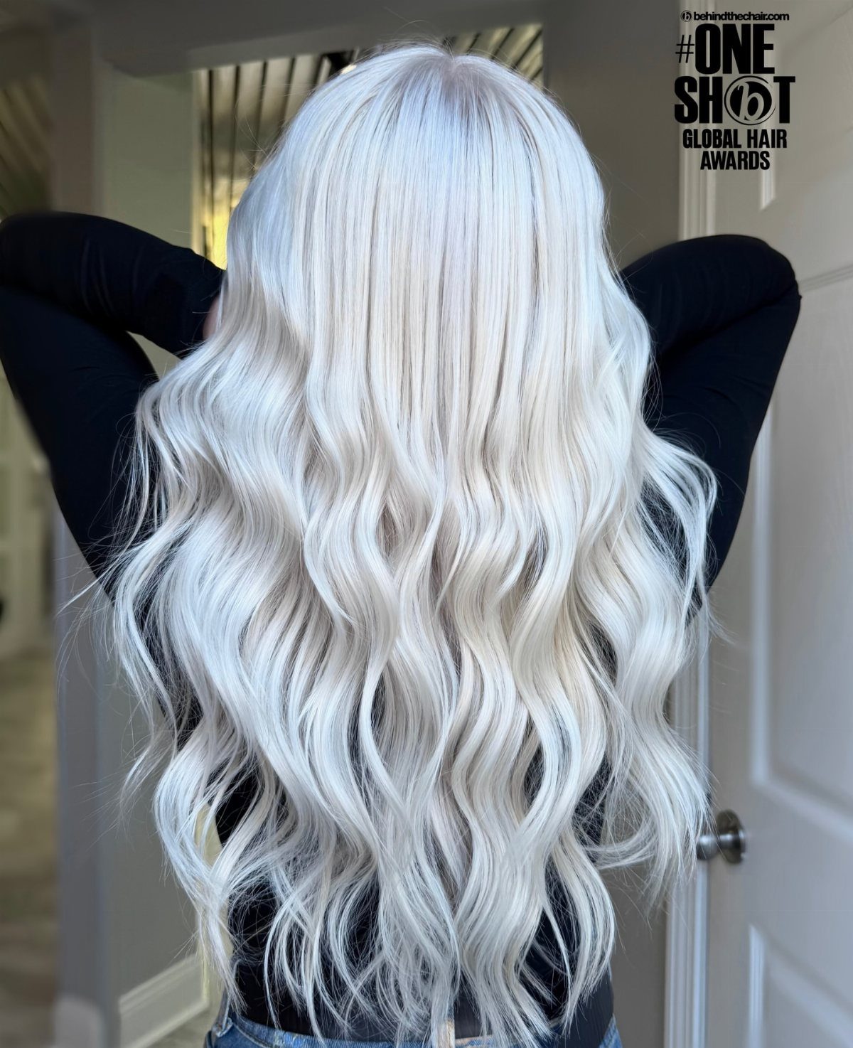Long icy platinum blonde waves fall over a dark top