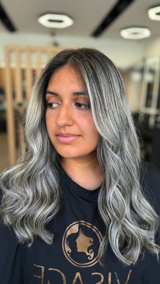 Woman with long, wavy ash icy blonde hair and darker roots