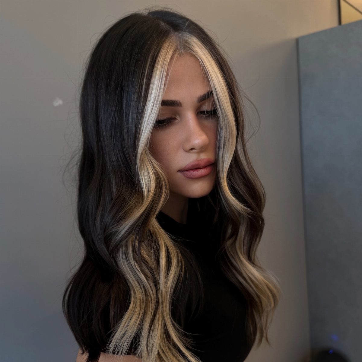 Woman with long dark waves and contrasting blonde face-framing streaks