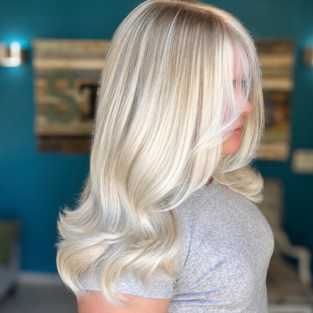 Pale blonde layered hair with curled ends shown in profile