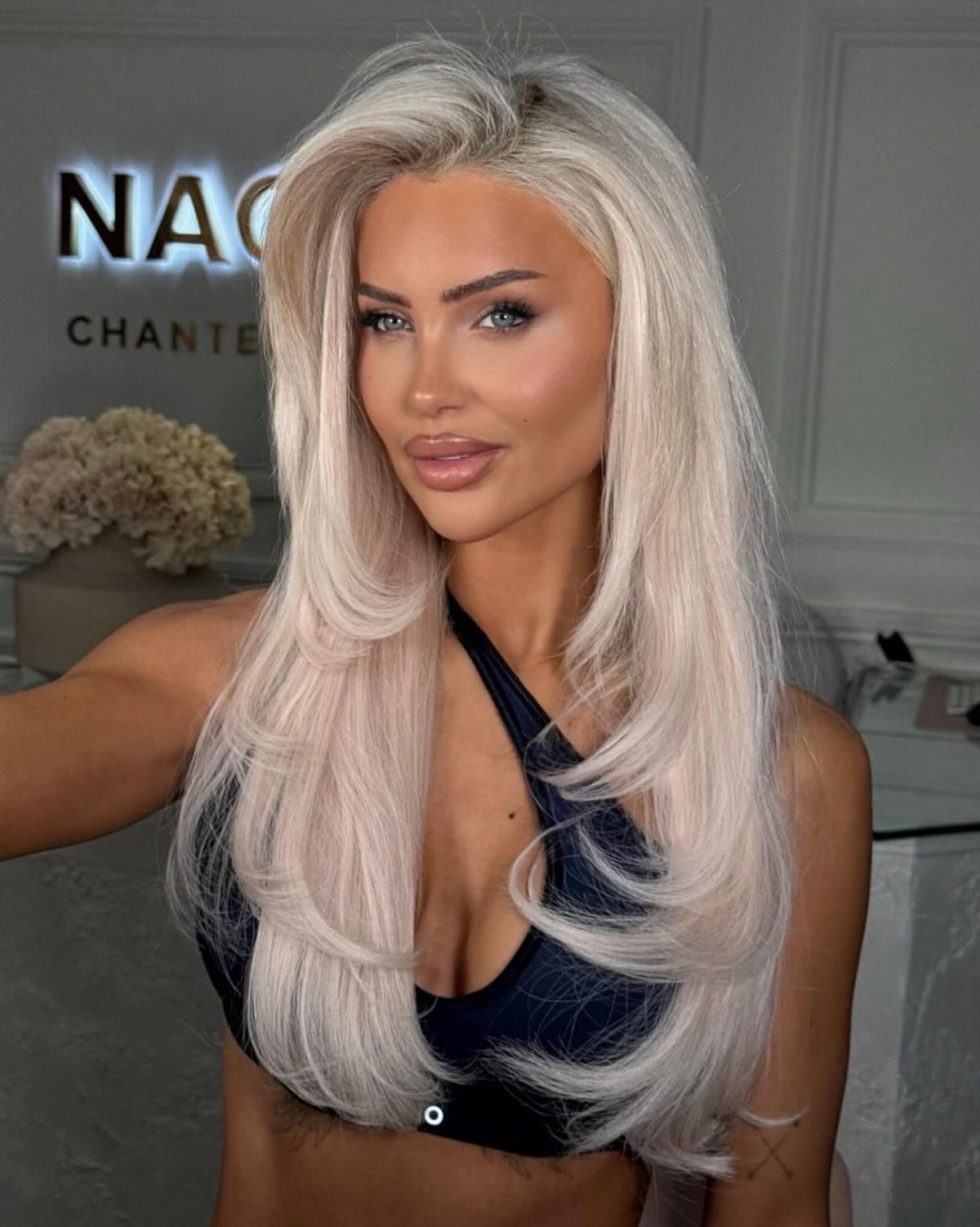 Woman poses with long, all-over platinum blonde hair in a salon