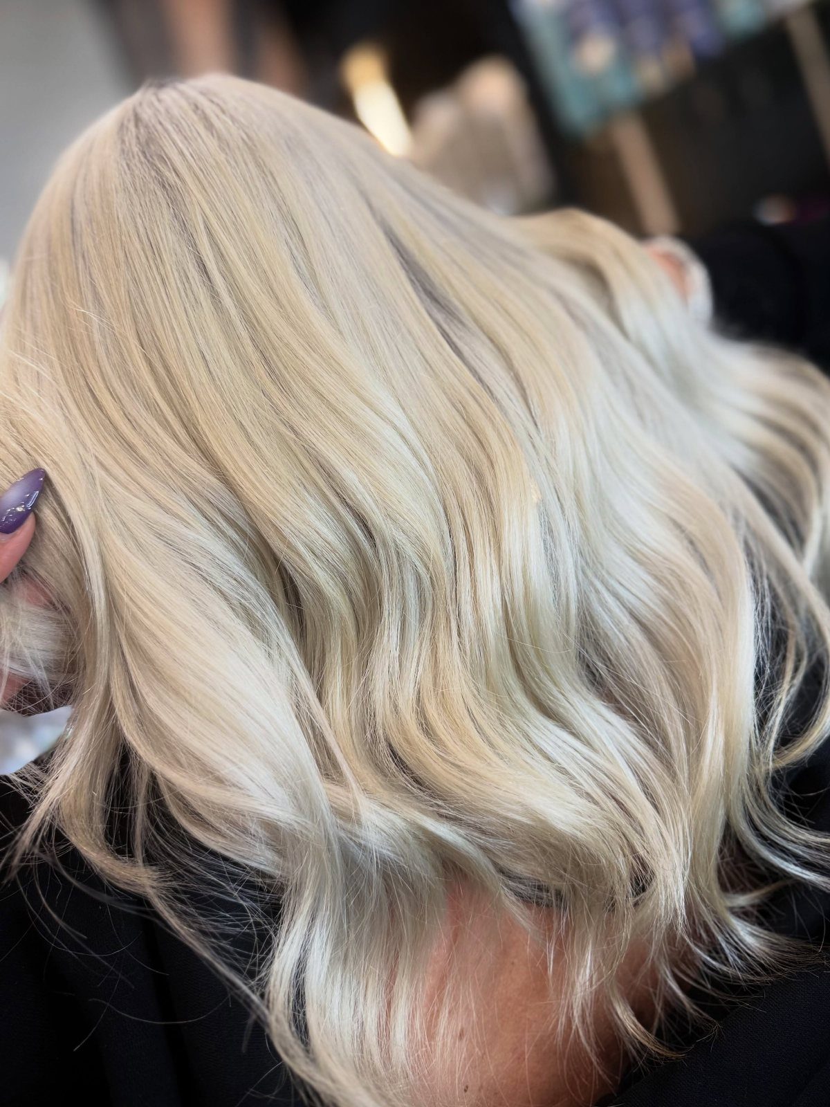 Icy blonde waves with delicate fine highlights shown from behind in a salon