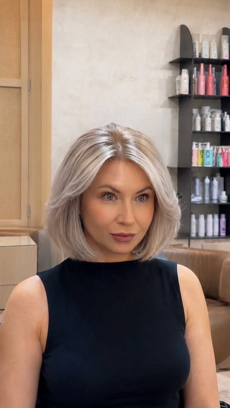 Woman with a chin-length icy blonde bob seated in a hair salon