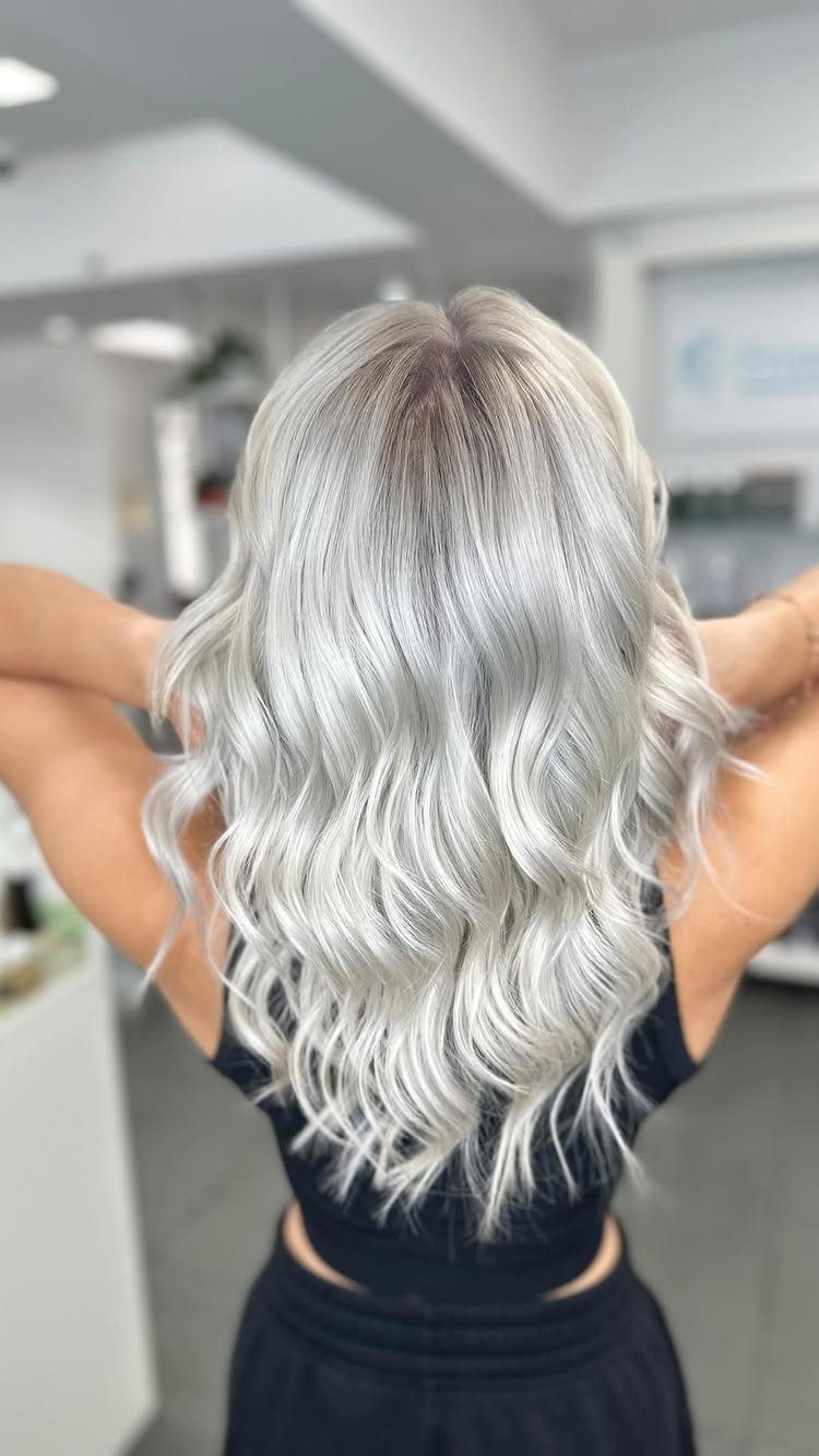 Icy blonde curls fall down the back of a person in a salon