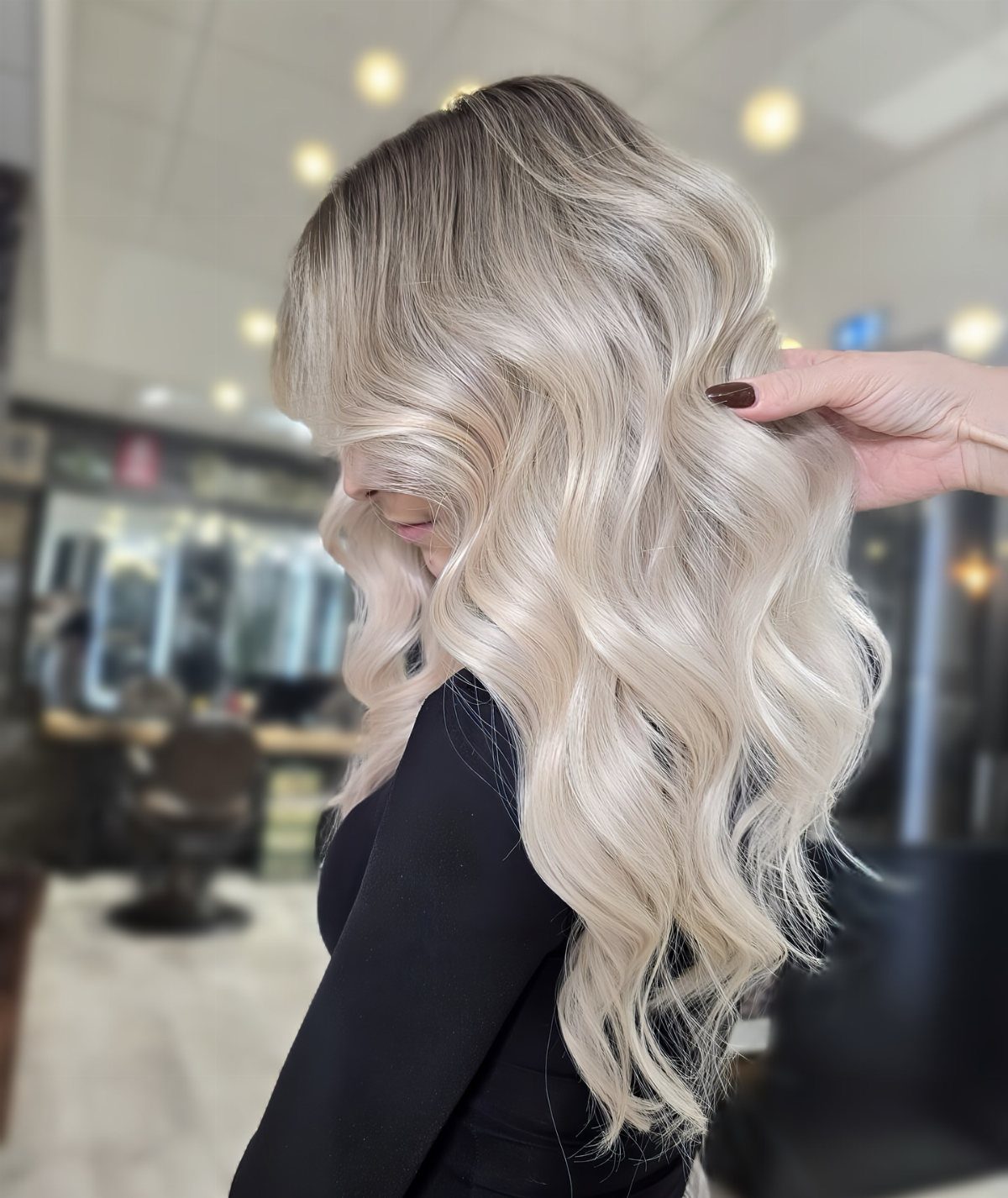 Long wavy icy blonde hair transitions from dark roots to platinum ends
