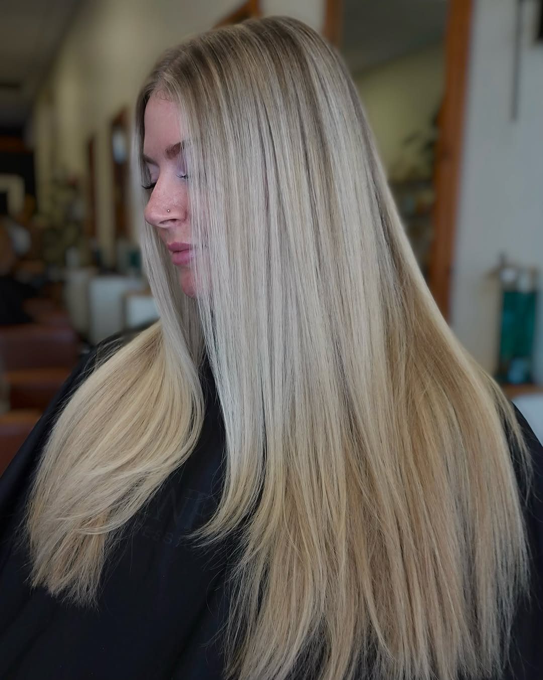 Long icy blonde hair falls straight down a woman's back in a salon