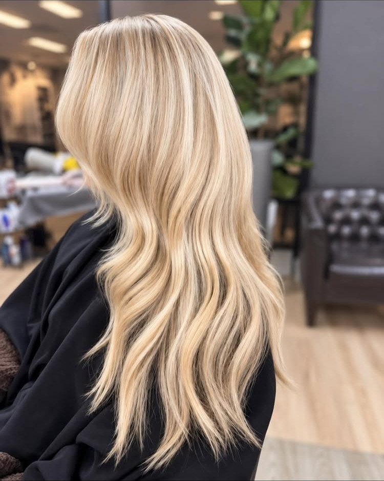 Long wavy blonde hair blends pale platinum strands with warm sandy tones