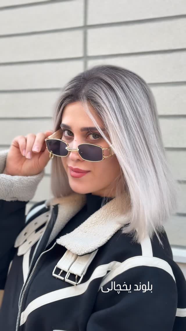 Woman showing straight, shoulder-length icy silver-blonde hair against a tiled wall