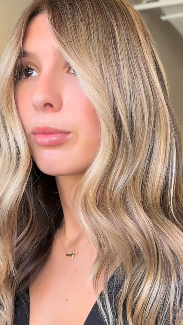 Woman with long beige blonde and light brown waves and darker roots