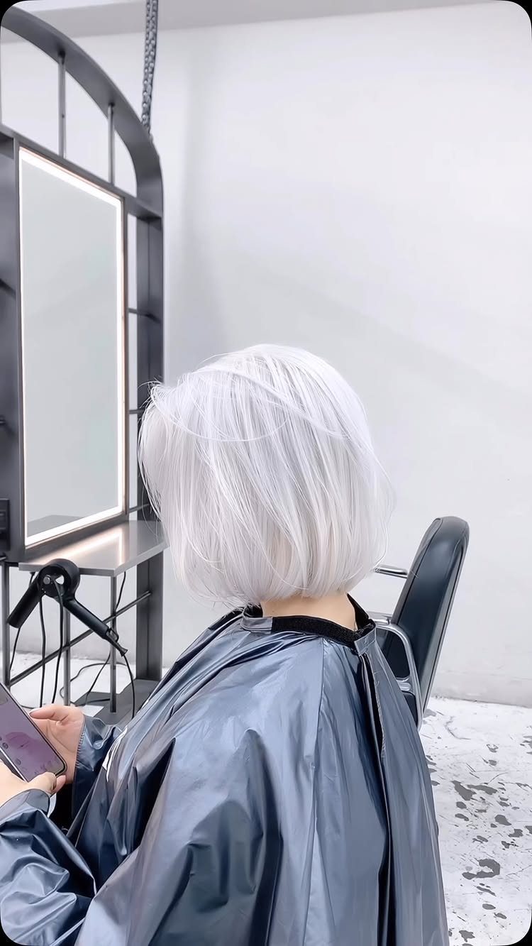 Short white-blonde bob seen from behind in a salon chair