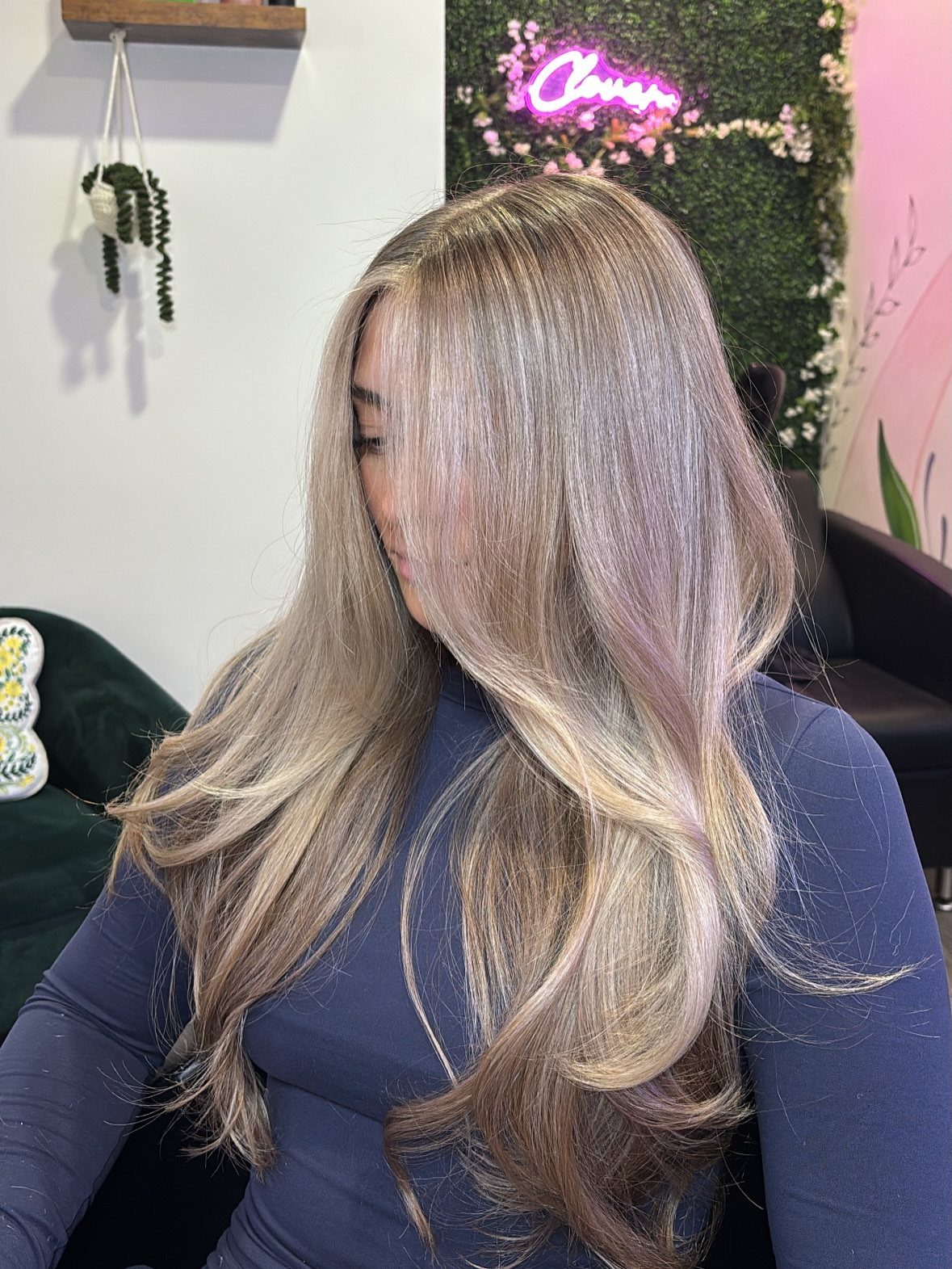 Woman showing long layered blonde hair with darker roots and curled ends