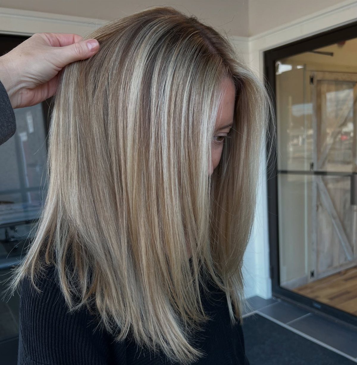 Beige blonde shoulder-length hair with darker roots, lifted to show its color