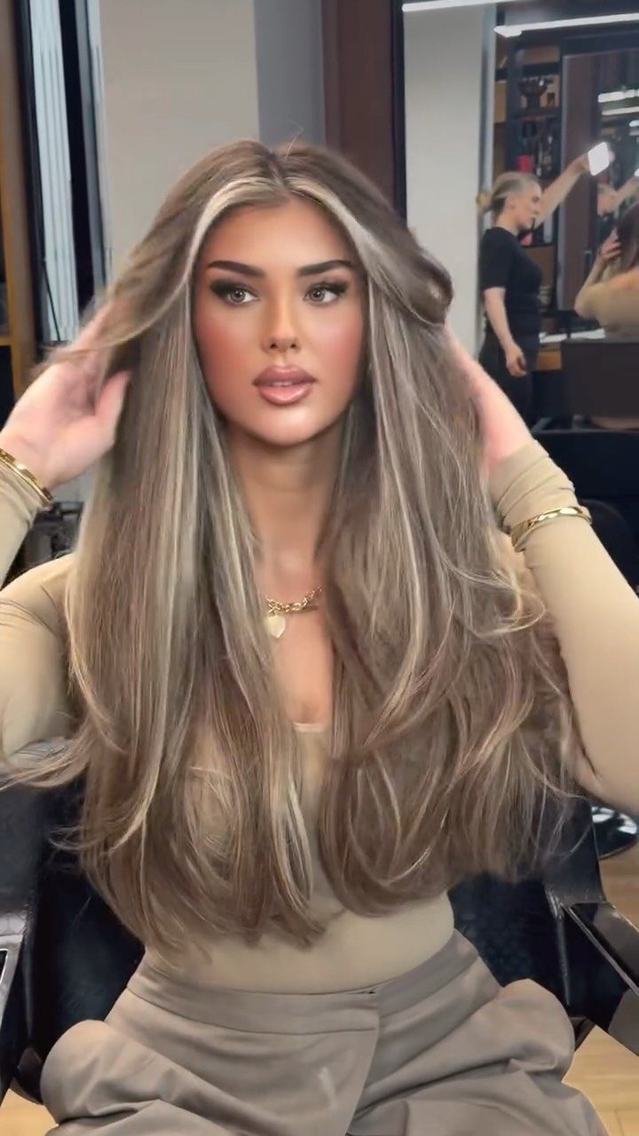 Woman with long, cool-toned ash-blonde hair seated in a salon chair