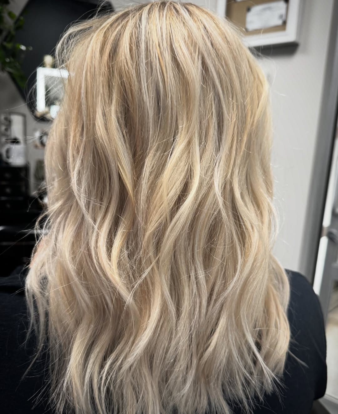 Long blonde hair with darker roots styled in loose, tousled waves