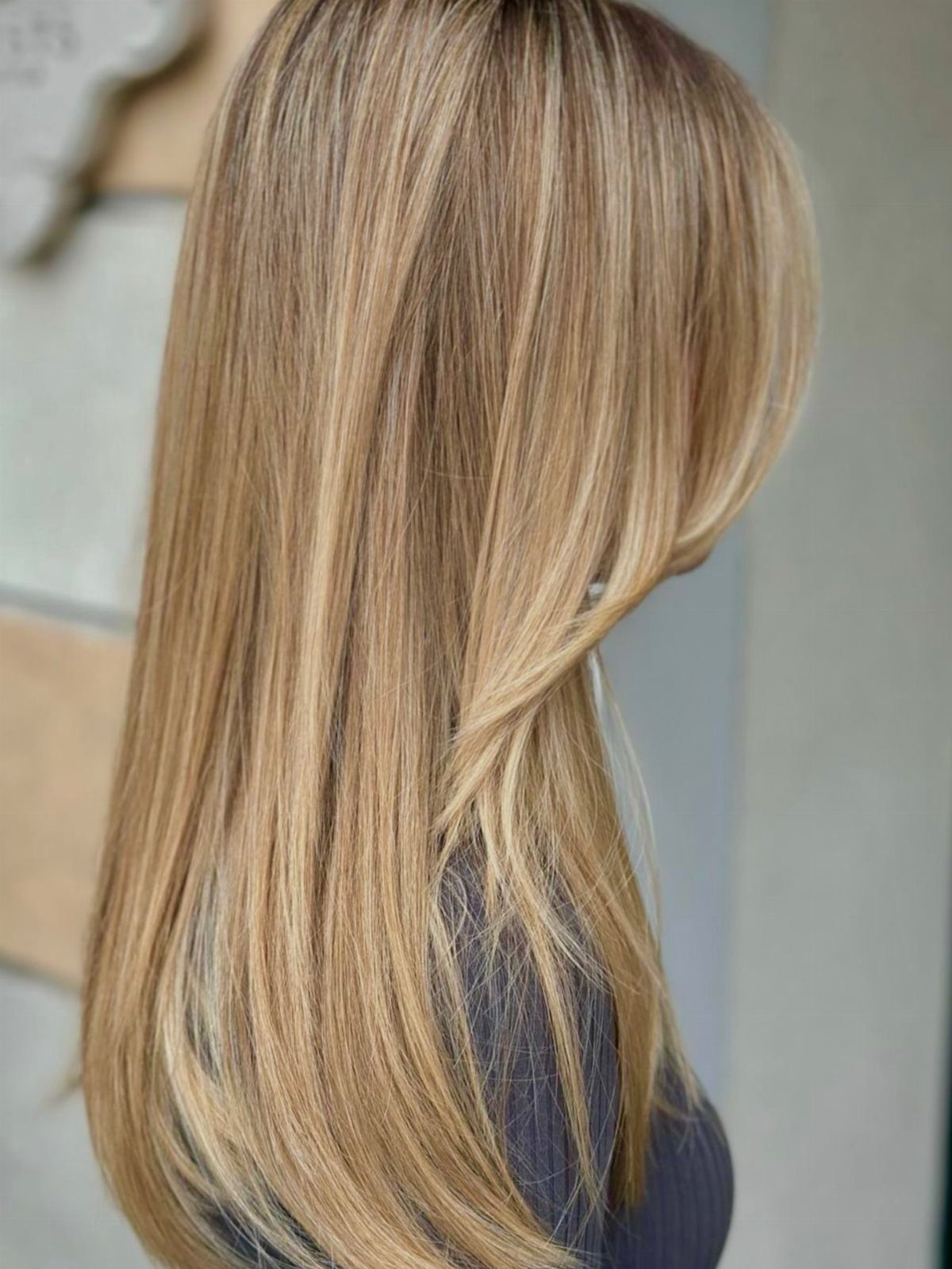 Long honey blonde hair falls smoothly down the back in warm golden strands