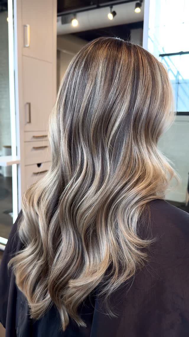Long wavy blonde hair with darker roots and blended lighter highlights