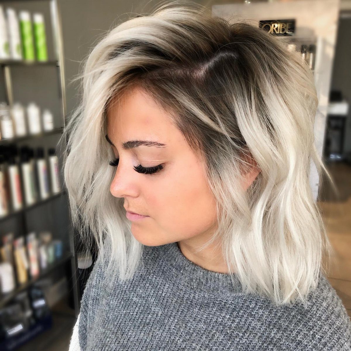 Pale blonde hair with dark roots and loose waves in a salon
