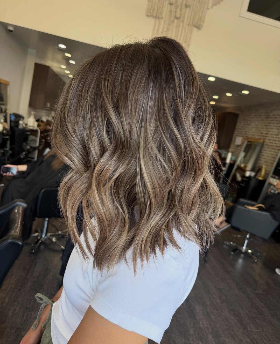 Shoulder-length wavy dirty blonde hair with highlights in a salon